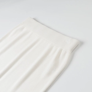 Detail of white knit skirt featuring elastic ribbed waistband and vertical striped texture