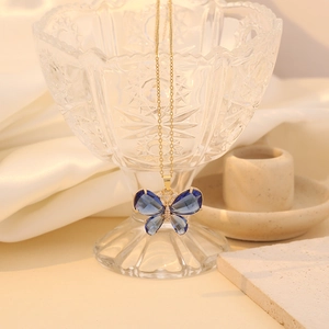 Elegant gold butterfly necklace featuring a dark blue pendant on polished silk background