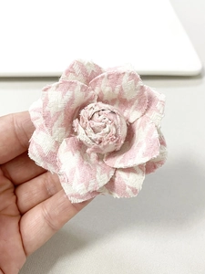 Detail of pink and white herringbone fabric camellia brooch with layered petals