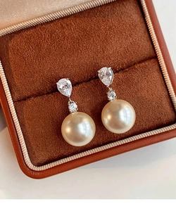Gros plan de boucles d'oreilles perles dorées et zircons sur un fond en velours