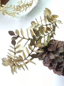 Detail of golden olive leaf hair comb with textured veins on natural pine cone background