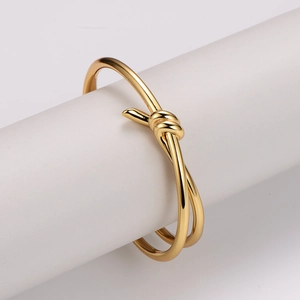 Elegant gold-plated knot bangle with a minimalist intertwined design on white display