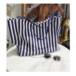 Blue and white striped canvas tote bag displayed on marble surface with sunglasses