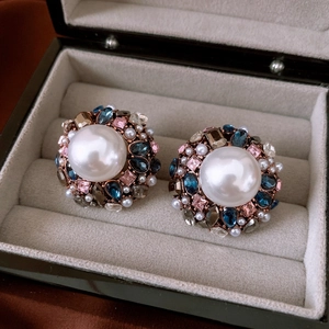 Macro shot of vintage round earrings with pearls and colorful rhinestones in a jewelry box