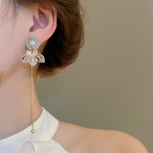 Close-up of gold tassel earrings with crystal petals and pavé studs on model