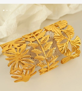Detailed view of gold leaf hollow bracelets arranged on a natural stone background