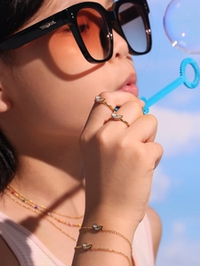 Gros plan de bagues et bracelets nuage arc-en-ciel dorés sur la main d'un enfant