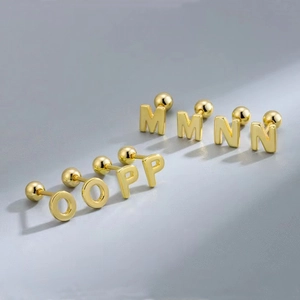 Detail view of golden stainless steel alphabet studs showing letters M, N, O, and P
