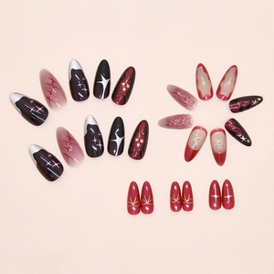 Detail of almond-shaped press on nails featuring red gradients and golden star motifs