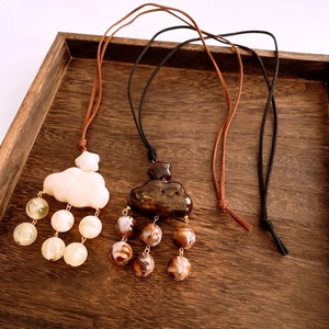 Detailed view of marble resin cloud pendants and beaded necklace on a wooden tray