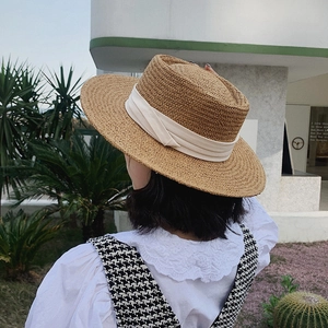 Flat top straw sun hat with white ribbon decoration for summer beach vacations