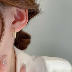 Close-up of a model wearing a minimalist interlocking geometric gold earring