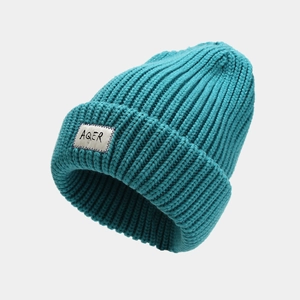 Teal blue chunky knit beanie hat for women featuring a white square AQER logo patch