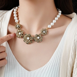 Detail of vintage flower charms and white faux pearls on an elegant necklace