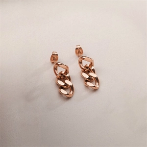 Detailed view of rose gold curb chain earrings with polished finish on marble background