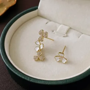 Asymmetric zircon flower stud earrings with gold plating and white enamel petals