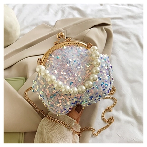 Close-up of sparkling sequin handbag with pearl handle and gold metal frame