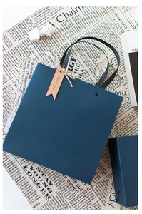 Detail of dark blue gift paper bag with black ribbon handle and Thank You tag