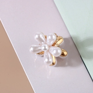 Detail of flower hair claw with white faux pearls and golden alloy floral base