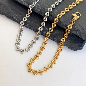 Detail of 18k gold heart link bracelet on black textured stone background