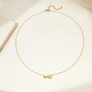 Detailed close-up of golden infinity necklace featuring a sparkling cubic zirconia pendant