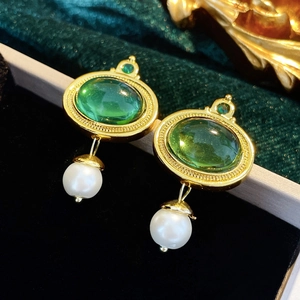 Détail de boucles d'oreilles vintage dorées avec pierres vertes et pendentifs perles
