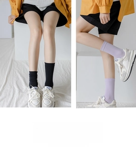 Detailed view of mid-calf cotton socks in black and lavender with white sneakers