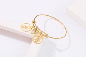Detailed shot of gold adjustable bangle featuring boy girl and heart shape charms
