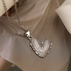 Elegant silver heart pendant necklace with shimmering cubic zirconia on grey fabric