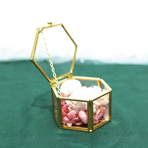 Detail of hexagonal gold glass jewelry box with preserved flowers and wedding ring inside