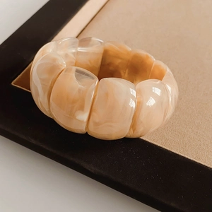 Close-up of geometric acrylic cuff bracelet with cream and orange marble texture