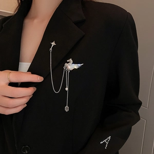 Detailed close-up of a silver swan brooch with crystals and tassel chain on a suit jacket