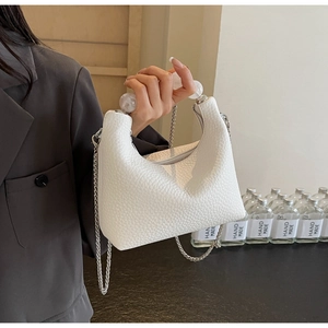 Detail of white lychee leather handbag with spherical handle and silver chain strap