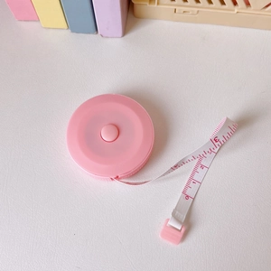 Close-up of pink round mini retractable measuring tape with central button for sewing