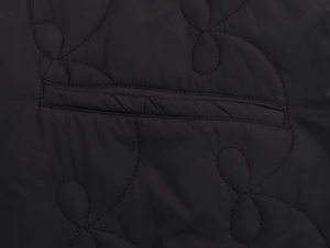 Détail du motif matelassé floral et poche pratique sur une veste noire étanche