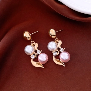 Detail of French vintage gold earrings featuring white and pink pearls on brown silk fabric