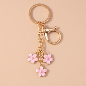 Close-up of pink cherry blossom keychain with metal lobster clasp on a beige background