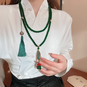Close-up of vintage Chinese style long beaded necklace with green tassels and painted pendant