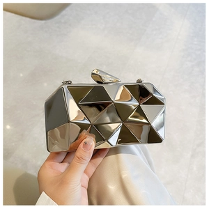 Detail of silver geometric acrylic clutch with 3D faceted metallic surface for evening gala