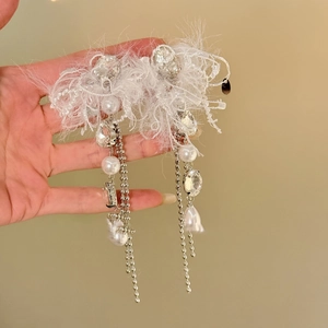 Détail de boucles d'oreilles à pompons plumes blanches avec strass, perles et argent