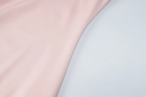 Close-up detail of soft pink smooth fabric texture on elegant off-shoulder dress