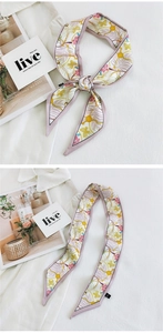 Detailed view of long pink silk scarf with butterfly and floral patterns on white shirt