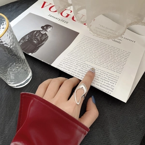 Irregular silver s925 ring on hand over a Vogue magazine with an aesthetic background