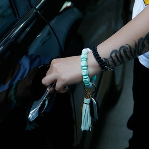 Detail view of a mint green silicone beaded wristlet keychain with leather tassel and gold ring