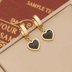 Detailed macro view of heart-shaped gold-tone earrings with black enamel on a display box