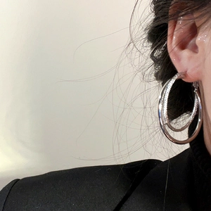 Modern double layered silver hoop earrings shown on model profile for a layered metallic look