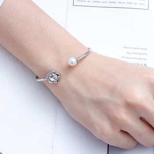 Detail of silver titanium steel open cuff bracelet with flower crystal and white pearl