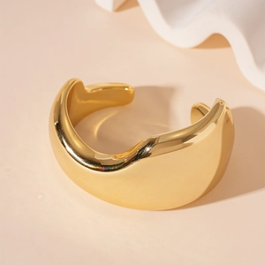 Detail of chunky gold irregular geometric bangle with polished mirror finish and open cuff