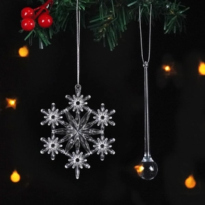 Macro detail of clear acrylic snowflake and drop ornaments with festive silver hanging cords