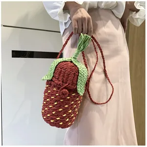Close-up of handmade strawberry crochet bag with green leaves and red knit texture